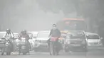 Seorang pengendara sepeda dengan wajah ditutupi masker melintasi sebuah jalan di pagi hari yang dingin dan berkabut di New Delhi pada tanggal 18 November 2024. (Money SHARMA/AFP)