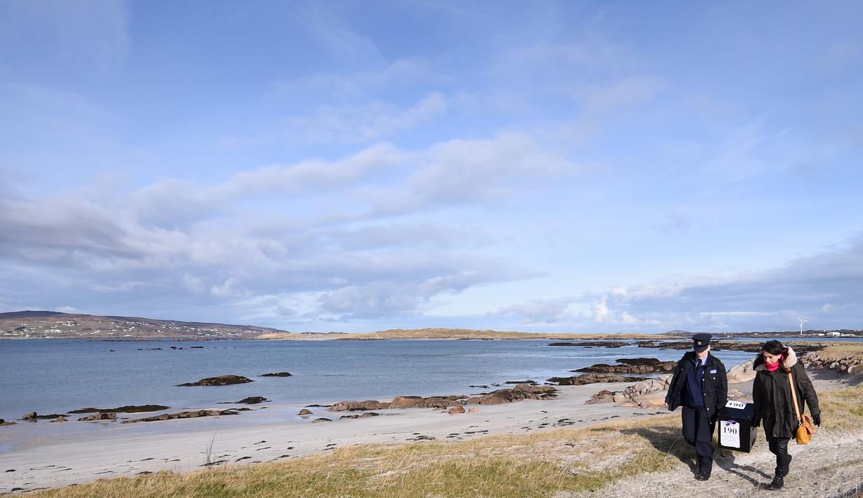 Polisi wanita Irlandia, Margaret Byrne dan pejabat ketua, Majella Harkin mengawal kotak suara ke pulau Innisfree, Irlandia, (25/2). Margaret seorang diri mengawal dan mengantarkan logistik pemilu ke pulau terpencil Irlandia. (REUTERS/Clodagh Kilcoyne)
