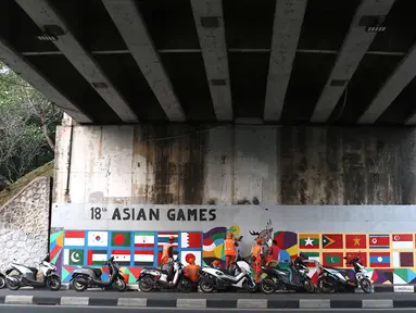 Petugas PPSU Srengseng Sawah menggambar mural bertema Asian Games 2018 di kolong flyover Universitas Indonesia, Depok, Jawa Barat, Jumat (27/7). Mural dibuat dalam rangka menyambut perhelatan Asian Games 2018. (Liputan6.com/Immanuel Antonius)
