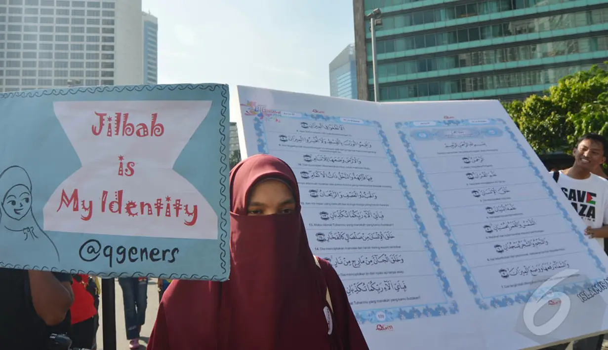 Seorang perempuan berdiri di depan Alquran raksasa yang dibawa mengelilingi Bundaran HI, Jakarta, Minggu (21/12/2014). (Liputan6.com/Herman Zakharia)