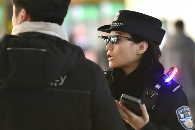 Seorang polisi wanita di China mengenakan smartglasses atau kacamata pintar dengan sistem pengenalan wajah di Zhengzhou East Railway Station. (AFP)