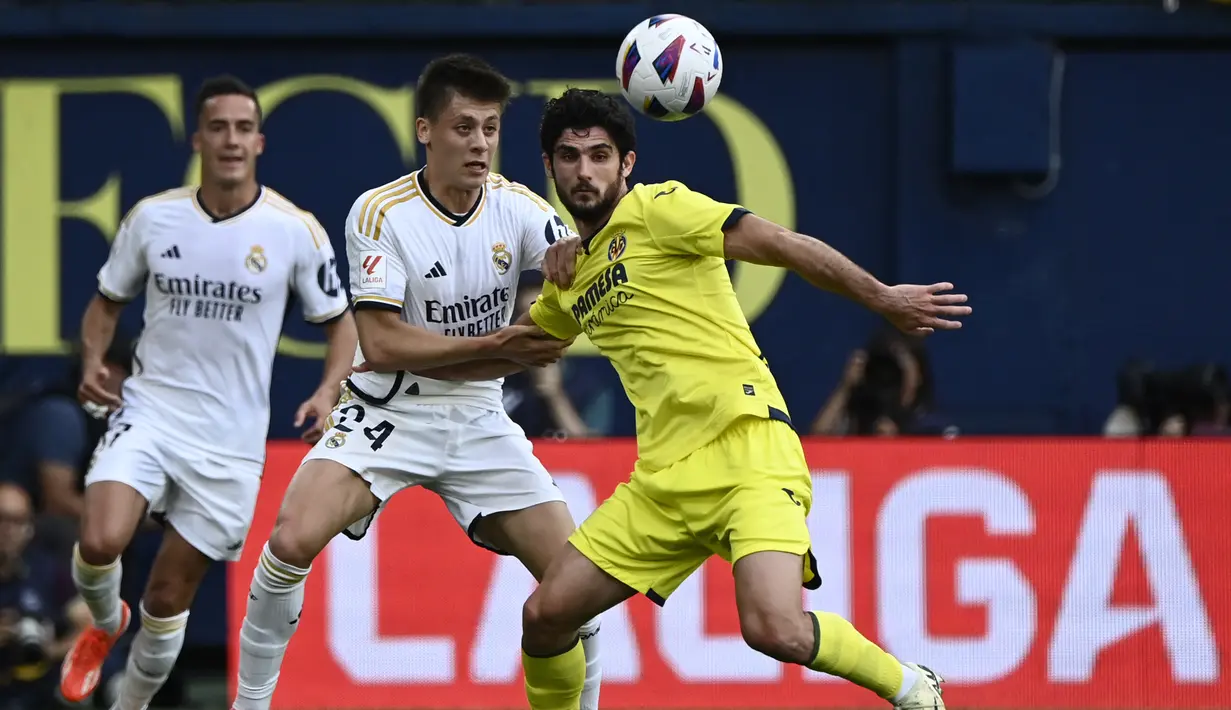 Gelandang Real Madrid #24 Arda Guler dan penyerang Villarreal #09 Goncalo Guedes berebut bola dalam laga jornada 37 La Liga 2023/2024 yang digelar di Estadio de la Ceramica, Senin (20/5/2024) dini hari WIB. (JOSE JORDAN / AFP)