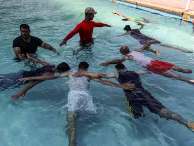 Anak muda Palestina yang diamputasi berlatih di bawah instruksi Majdi al-Tatar (kiri)  di kolam renang Kota Gaza (30/7/2019). Tatar, yang kehilangan kaki kanannya akibat kecelakaan pada masa kecilnya, melatih warga Palestina yang diamputasi selama konflik dengan Israel. (AFP Photo/Mahmud Hams)