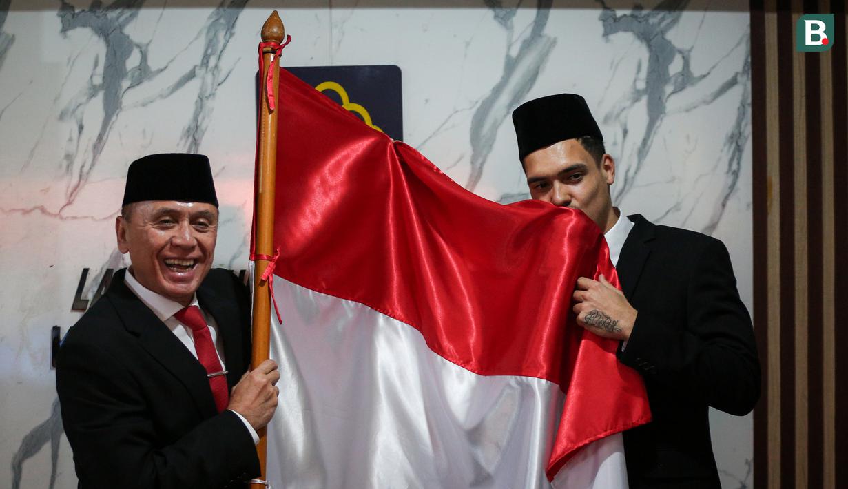 <p>Pemain Naturalisasi Timnas Indonesia, Shayne Pattynama (kanan) mencium bendera merah putih bersama Ketua Umum PSSI saat Pengambilan Sumpah Janji Setia Pewarganegaraan Republik Indonesia yang berlangsung di Kantor Wilayah Kementetian Hukum dan HAM DKI Jakarta, Selasa (24/01/2023). (Bola.com/Bagaskara Lazuardi)</p>