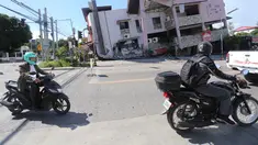 Orang-orang yang mengendarai sepeda motor melewati bangunan yang runtuh setelah gempa bumi di General Santos, Filipina, Senin 8 Juni 2026. (AP Photo)
