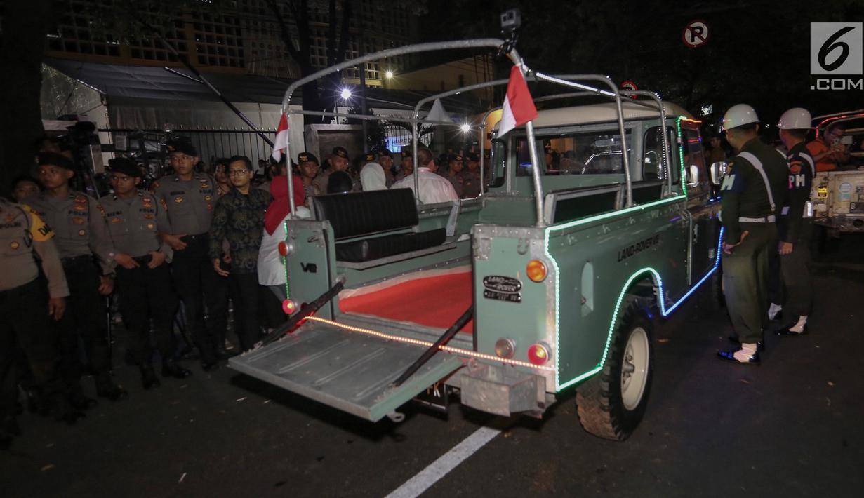 Petugas mengatur parkir mobil Land Rover klasik bak terbuka tumpangan Jokowi-Ma`ruf di gedung KPU Pusat, Jakarta, Jumat (21/9). Jokowi-Ma`ruf ke KPU untuk mengambil nomor urut Pilpres pasangan Capres dan Wapres 2019- 2024. (Liputan6.com/Fery Pradolo)
