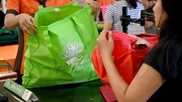 Karyawan mengemas barang belanjaan konsumen dengan tas belanja nonplastik di sebuah supermarket di Denpasar, 16 Juli 2019. Bali menerapkan pelarangan penggunaan plastik sekali pakai yang tertuang dalam Peraturan Gubernur (Pergub) Nomor 97 Tahun 2018. (SONNY TUMBELAKA/AFP)