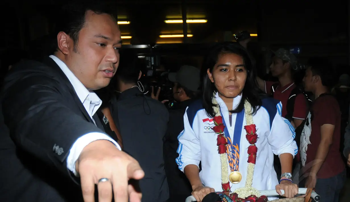 Sekretaris Jendral PBSI, Anton Subowo (kiri), mengawal salah satu pebulutangkis ganda putri peraih emas Asian Games 2014, Nitya Krishinda, di Bandara Soekarno-Hatta, Selasa (30/9/2014). (Liputan6.com/Helmi Fithriansyah)