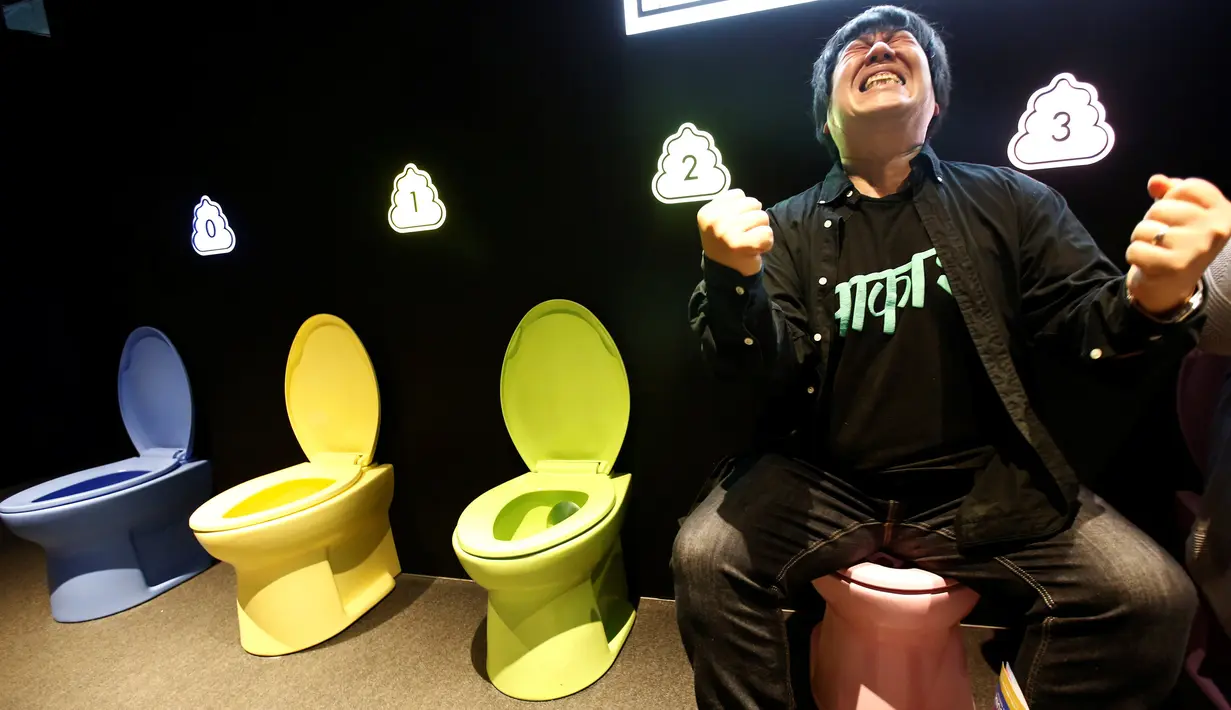 Pengunjung berpura-pura buang air besar di di toilet pajangan yang dipamerkan di Museum Unko di Yokohama, Jepang pada Rabu (17/4). Kali ini, Negeri Sakura itu baru saja membuka sebuah museum pop-up bertema unik dan tak biasa, yaitu tinja atau kotoran (poop). (REUTERS/Kim Kyung-hoon)