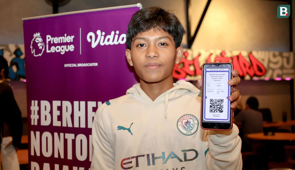 Seorang fans Man City memperlihatkan tiket pembelian Roaring Night Liga Inggris 2023/2024 antara Manchester City melawan Arsenal di Hype Cafe, Depok, Minggu (31/3/2024) malam. (Bola.com/Abdul Aziz)