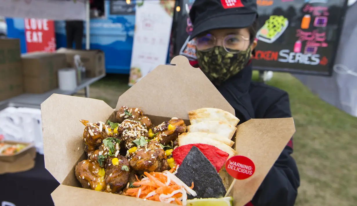 Penjual yang mengenakan masker memperlihatkan hidangan ayam goreng saat Festival Ayam Goreng di Toronto, Kanada, 20 September 2020. Festival yang digelar di tengah pandemi COVID-19 tersebut berlangsung pada 19-20 September 2020 dengan menghadirkan sekitar 30 jenis ayam goreng. (Xinhua/Zou Zheng)