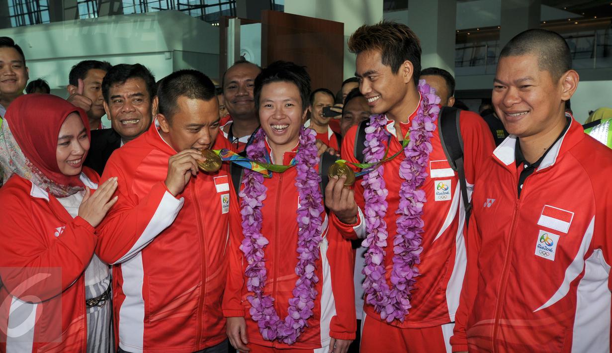 Menpora Imam Nahrawi menggigit medali emas saat menyambut kedatangan Tontowi  Ahmad dan Lilyana Natsir di Bandara Soetta, Banten, Selasa (23/8/2016). Tontowi Ahmad/Lilyana Natsir berhasil meraih emas olimpiade Rio 2016. (Liputan6.com/HelmiFithriansyah)