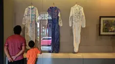 Dua orang melihat hazmat yang ditandatangani dan disumbangkan oleh tim medis dari Guangdong dan Hainan saat mendukung Provinsi Hubei selama lockdown COVID-19 di ruang Pameran Revolusi Wuhan, Wuhan, China, 5 Agustus 2020. (Photo by Hector RETAMAL/AFP)