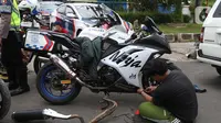 Pengendara motor mencopot knalpot bising usai terjaring razia yang digelar Satlantas Polres Metro Depok di Jalan Margonda Raya, Depok, Kamis (18/3/2021). Puluhan motor berknalpot bising yang terjaring razia diwajibkan mengganti knalpot dan diberi sanksi tilang. (Liputan6.com/Helmi Fithriansyah)