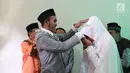 Komedian Caisar Aditya Putra mendapat ciuman di tangan oleh Intan Sri Mardiani usai melangsungkan ijab kabul pernikahan di kawasan Cimahpar, Bogor, Jawa Barat, Sabtu (30/6). (Liputan6.com/Herman Zakharia)