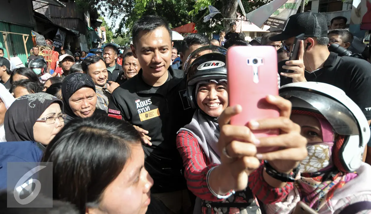  Warga Johar Baru berfoto dengan Cagub DKI Jakarta Agus Harimurti Yudhoyono, Jakarta, Senin (20/12). Saat mendatangi kawasan Johar Baru, Agus banyak mendengarkan keluhan warga tentang Jakarta saat ini. (Liputan6.com/Yoppy Renato)