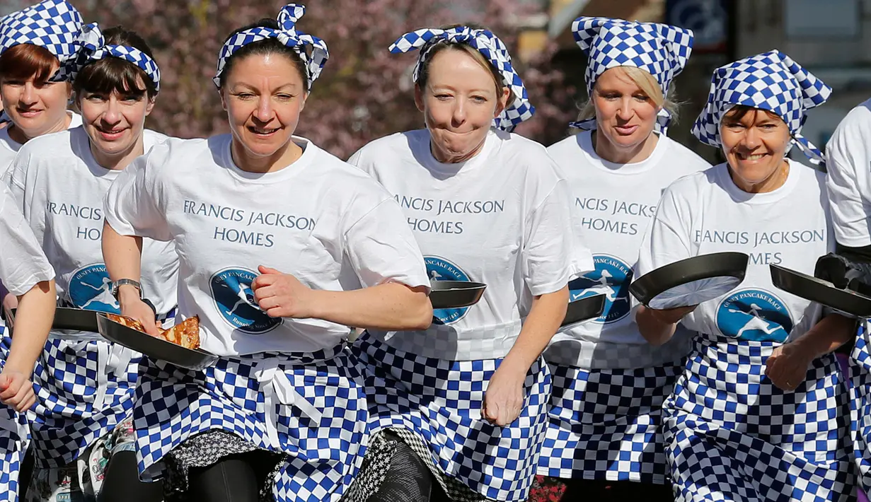 Para peserta melakukan pemanasan sebelum lomba lari dengan membawa pancake dalam lomba tahunan Pancake Trans-Atlantic, di kota Olney, Buckinghamshire, Inggris, Selasa (5/3). Peserta harus membolak-balikan pancake sambil tetap berlari. (AP/Frank Augstein)