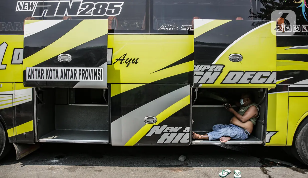 Seorang awak bus antarkota antarprovinsi (AKAP) beristirahat di armadanya di Terminal Kalideres, Jakarta, Senin (26/4/2021). Pemerintah memperpanjang masa larangan mudik Lebaran yaitu mulai dari 22 April hingga 24 Mei 2021. (Liputan6.com/Faizal Fanani)