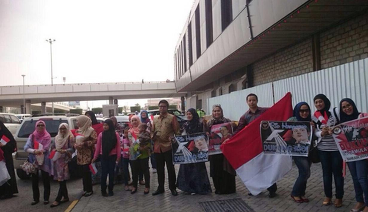 Warga Indonesia membawa bendera dan tulisan dukungan saat menyambut kedatangan pebalap Manor Racing asal Indonesia, Rio Haryanto, di Bandar Udara Internasional Bahrain, Selasa (29/3/206). (Bola.com/Twitter)