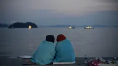Keluarga korban tenggelamnya kapal ferry Sewol tampak duduk di tepi pantai menanti kepastian kabar keluarganya yang ikut tenggelam 4 hari lalu (AFP Photo/ED Jones)
