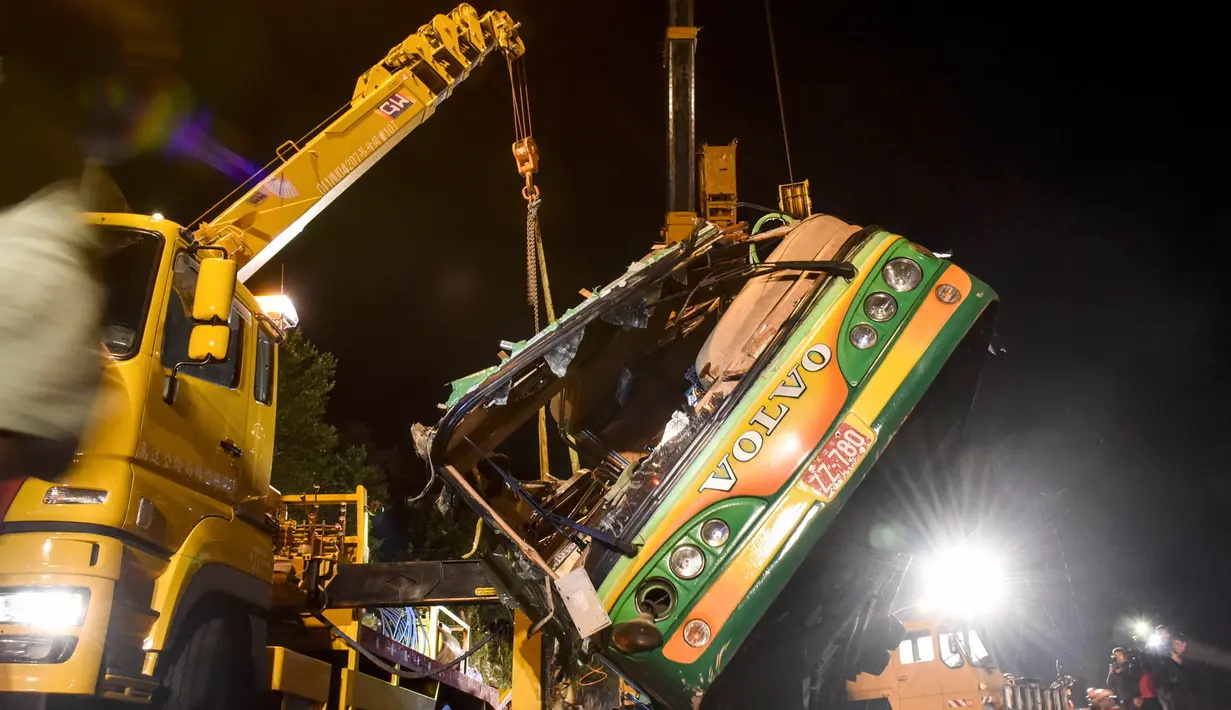 Alat berat mengevakuasi bangkai bus pariwisata Taiwan yang mengalami kecelakaan di ruas jalan dekat Taipe, Selasa (14/2). Kejadian nahas tersebut terjadi saat bus hendak membawa 44 turis berwisata melihat keindahan bunga sakura. (Ou Dongqu/Xinhua via AP)