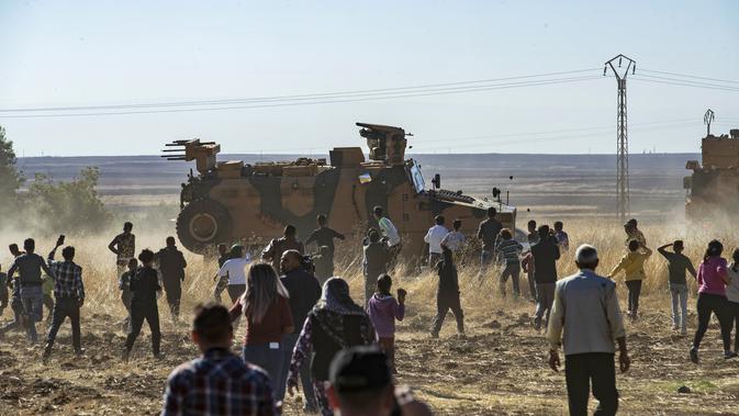 Sejumlah warga Kurdi melemparkan batu ke kendaraan militer Turki di dekat kota Al-Muabbadah, bagian timur laut Hassakah, Suriah (8/11/2019). Aksi dilakukan memprotes  terhadap serangan militer yang dilancarkan Turki. (AFP/Delil Souleiman)