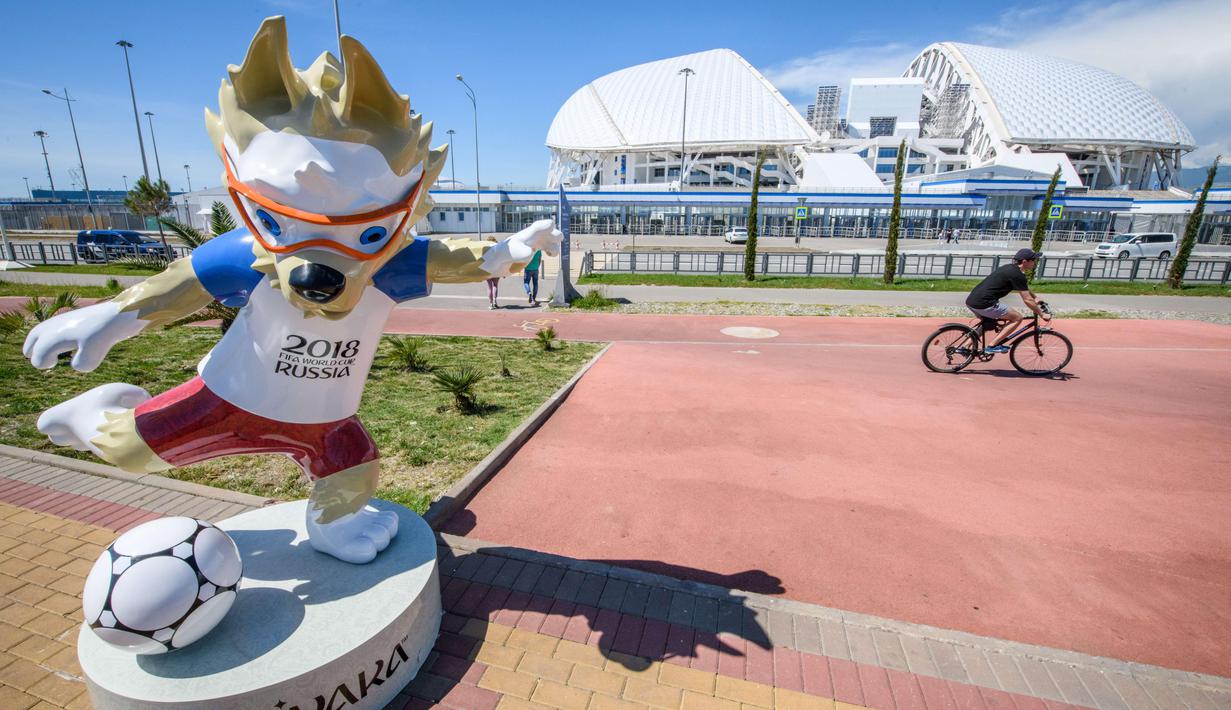 Warga melintas dekat maskot Piala Dunia 2018 di  Fisht Olympic Stadium ochi, Rusia, (17/5/2018). Stadion tersebut akan menjadi saksi laga perdana Portugal melawan Spanyol. (AFP/Mladen Antonov)