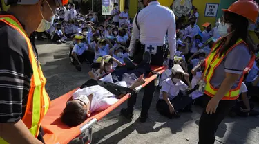 Seorang siswa digendong dengan tandu selama latihan gempa di sebuah sekolah dasar di Metro Manila, Filipina, Kamis (8/9/2022). Filipina melakukan latihan gempa nasional kuartal ketiga sebagai bagian dari upaya untuk membuat publik mengetahui protokol dan tanggapan selama bencana. (AP Photo/Aaron Favila)