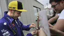 Pebalap Yamaha Movistar, Valentino Rossi, menyapa penggemarnya saat mendatangi paddock di Sirkuit Motegi, Tochigi Prefecture, Kamis (12/10/2017). MotoGP Jepang akan bergulir pada Minggu ini. (AP/Shizuo Kambayashi)