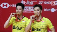 Ganda putra Indonesia Kevin Sanjaya Sukamuljo dan Marcus Fernaldi Gideon menggigit medali emas seusai mengalahkan ganda putra Cina Li Junhui dan Liu Yuchen pada babak final Indonesia Masters 2018 di Jakarta, Minggu (28/1). (Liputan6.com/Angga Yuniar)
