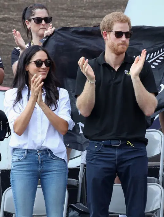 Pangeran Harry saat itu tampil dengan polo shirt berwarna hitam dan dipadukan dengan celana jeansnya. Sedangkan Meghan tampil dengan chic stylenya, dengan atasan putih dan celana jeans panjangnya. (AFP/Chris Jackson)