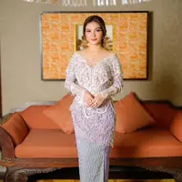 Selvi tampil mengenakan kebaya modern warna putih bergaya off shoulder dihiasi beads. Dipadukan kain warna ungu di bagian belakang dan putih di bagian depan. [@selvie_ananda_]