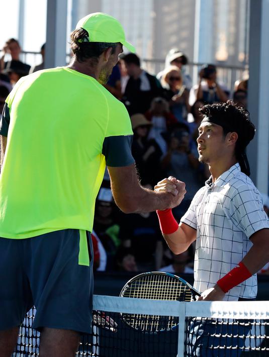 Petenis Kroasia, Ivo Karlovic dan petenis Jepang, Yuichi Sugita bersalaman seusai babak kedua turnamen Australia Terbuka 2018, Rabu (17/1). Memasuki usia 40 tahun, Karlovic memenangi duel dengan skor 7-6 (3), 6-7 (3), 7-5, 4-6, 12-10. (AP/Ng Han Guan)