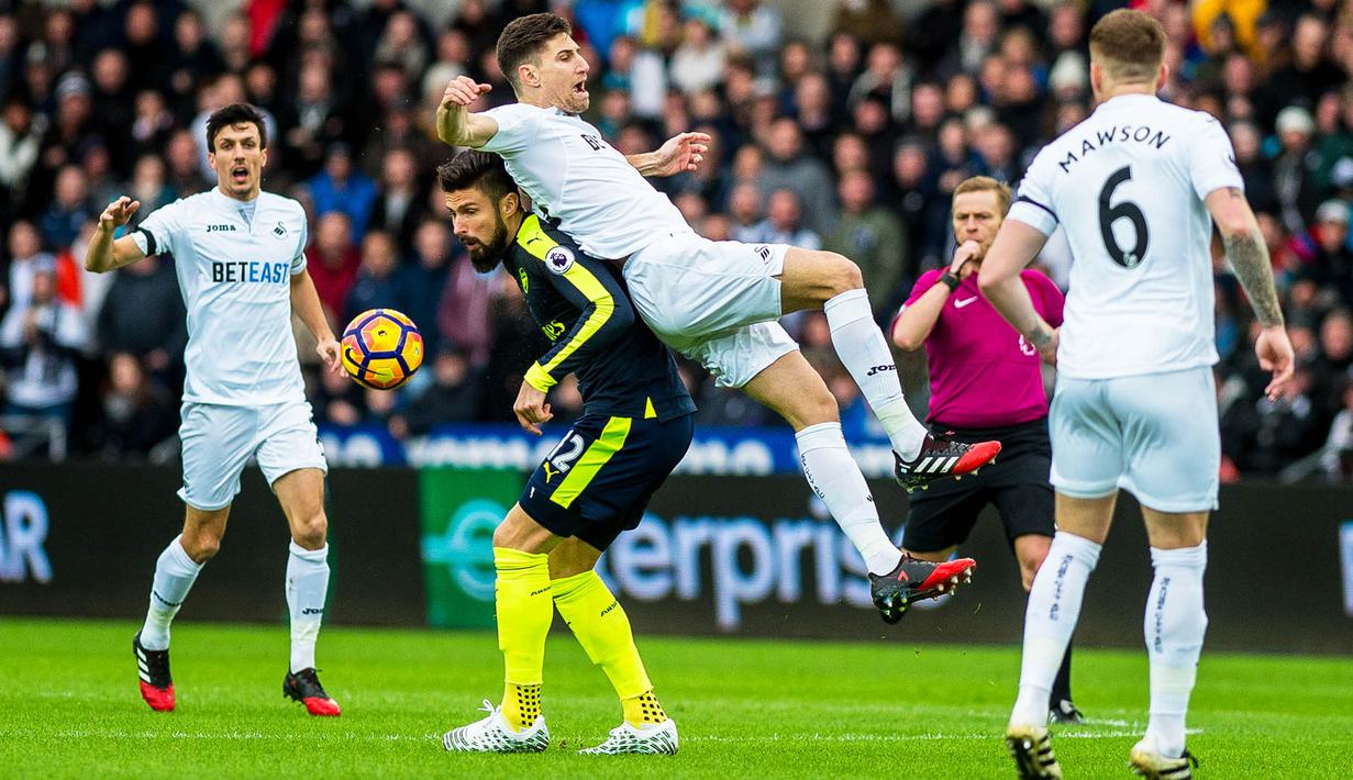 Striker Arsenal, Olivier Giroud, berebut bola dengan bek Swansea, Federico Fernandez. Meriam London menguasai jalannya laga dengan penguasaan bola 57 persen dan melakukan enam kali tembakan ke arah gawang. (EPA/Aled Llywelyn)