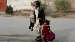 Seorang pria membawa kedua anaknya untuk menyalmatkan diri saat terjadi serangan di dekat kantor amal Inggris Save the Children di Jalalabad, Afghanistan (24/1). (AFP Photo/Noorullah Shirzada)
