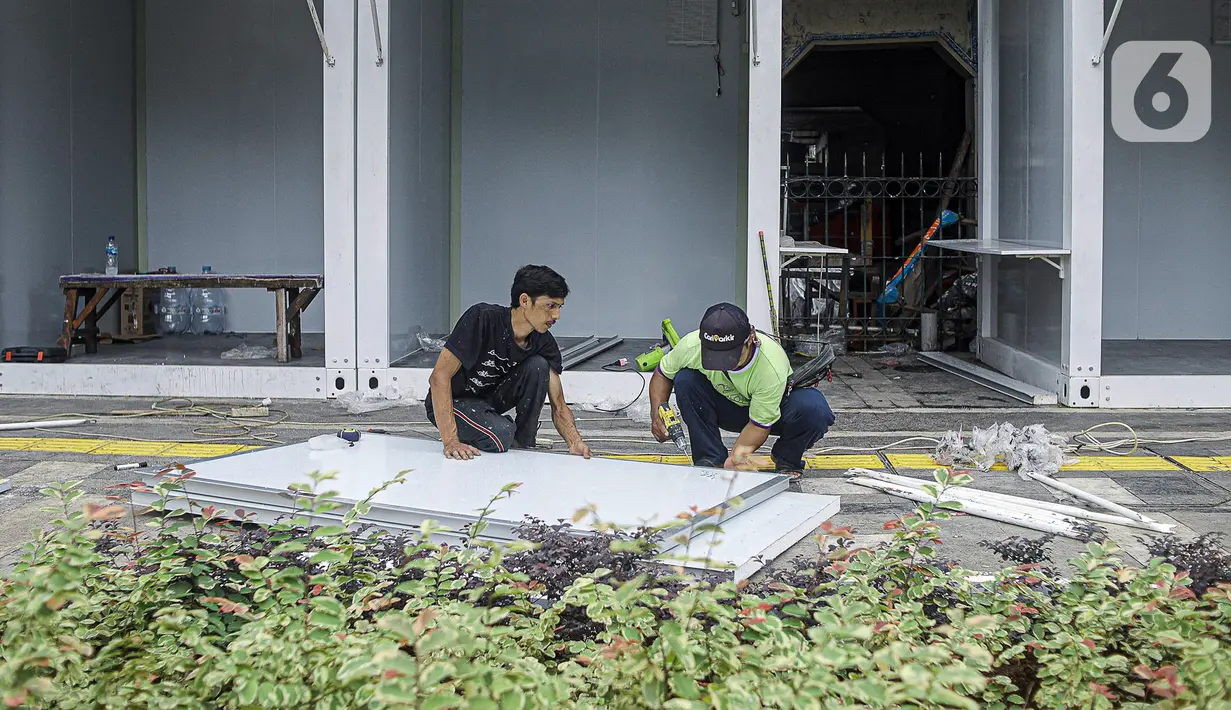 Para pekerja memasang kios untuk pedagang kaki lima (PKL) di atas trotoar usai direvitalisasi di kawasan Tugu Proklamasi, Menteng, Jakarta Pusat, Jumat (30/12/2022). Sebanyak 92 kios bongkar pasang dengan luas masing-masing 2x2 meter ini diperuntukkan bagi pedagang makanan agar lebih tertata rapi. (Liputan6.com/Faizal Fanani)