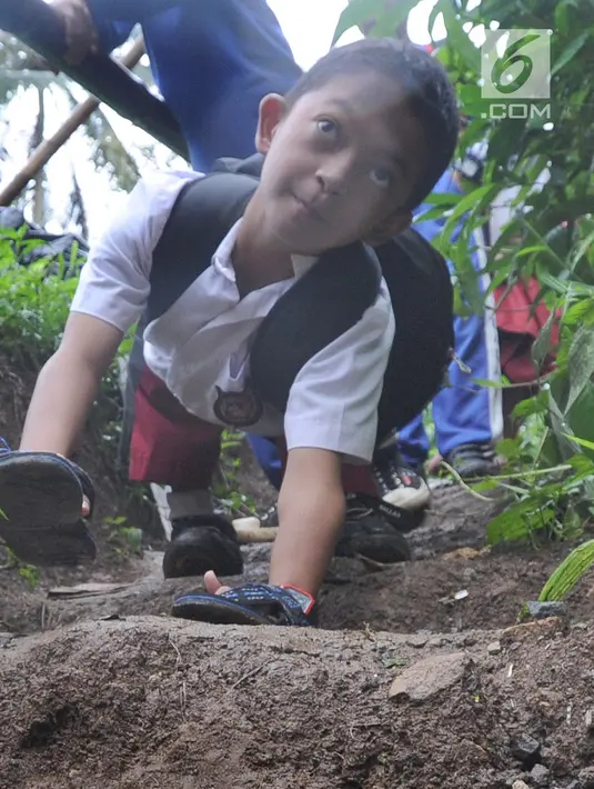 Mukhlis Abdul Holik (8) menuju sekolahnya di Kampung Cikiwul Tonggoh, Sekarwangi, Sukabumi, Kamis (15/11). Anak yang lahir pada 8 April 2010 tersebut diketahui mengalami kelainan fisik pada bagian kedua kakinya sejak lahir. (Merdeka.com/Arie Basuki)