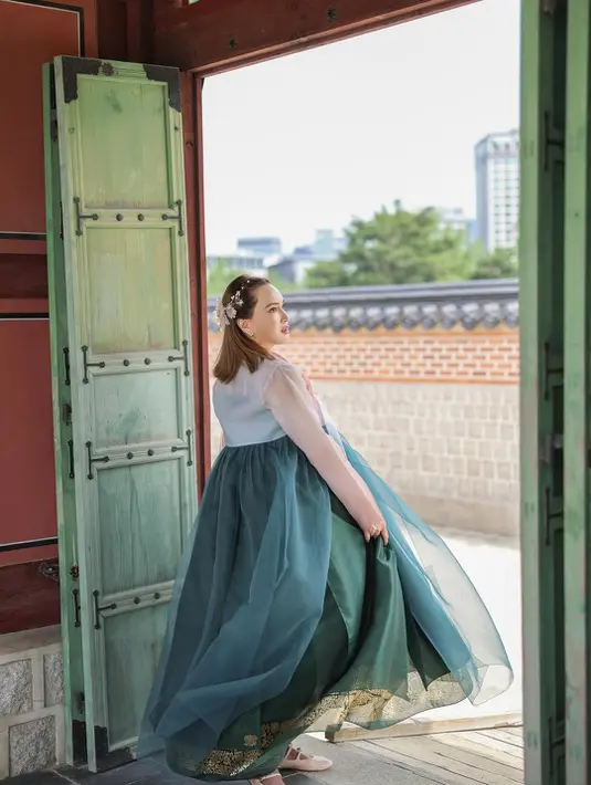 Sedangkan bagian bawah, yaitu chima atau rok hanbok, hadir dalam warna hijau botol yang mengembang indah dengan detail bordir emas di bagian hemline, menambah kesan mewah tanpa berlebihan. [@shandyaulia].