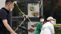 Wanita yang mengenakan masker mengobrol dekat restoran yang ditutup di Beijing, China, 15 Juni 2022. Otoritas China di Beijing menutup distrik perbelanjaan dan kehidupan malam utama menyusul lonjakan kasus COVID-19 terkait klub malam. (AP Photo/Ng Han Guan)