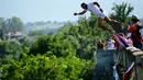 Seorang peserta bersiap melakukan terjun bebas dari jembatan Ura e Shejnt dalam kompetisi menyelam tradisional ke-68 di Gjakova, Kosovo, 22 Juli 2018. Kompetisi ini dilakukan dari ketinggian 22 meter. (AP/Visar Kryeziu)