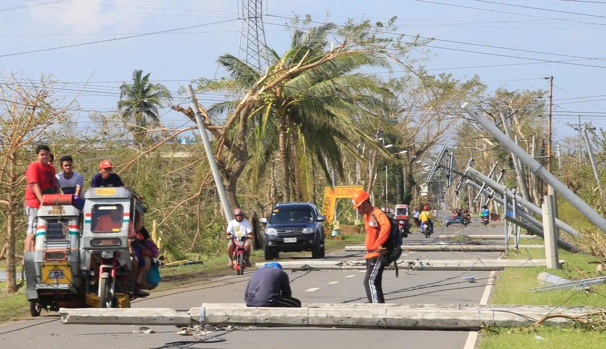 Sejumlah kendaraan melewati tiang listrik yang roboh akibat angin kencang yang disebabkan Topan Nock-ten di Kota Iriga Camarines Sur, Filipina tengah (27/12). Topan Nock-ten atau dikenal dengan Nina menerjang Filipina saat Natal. (REUTERS/Romeo Ranoco)