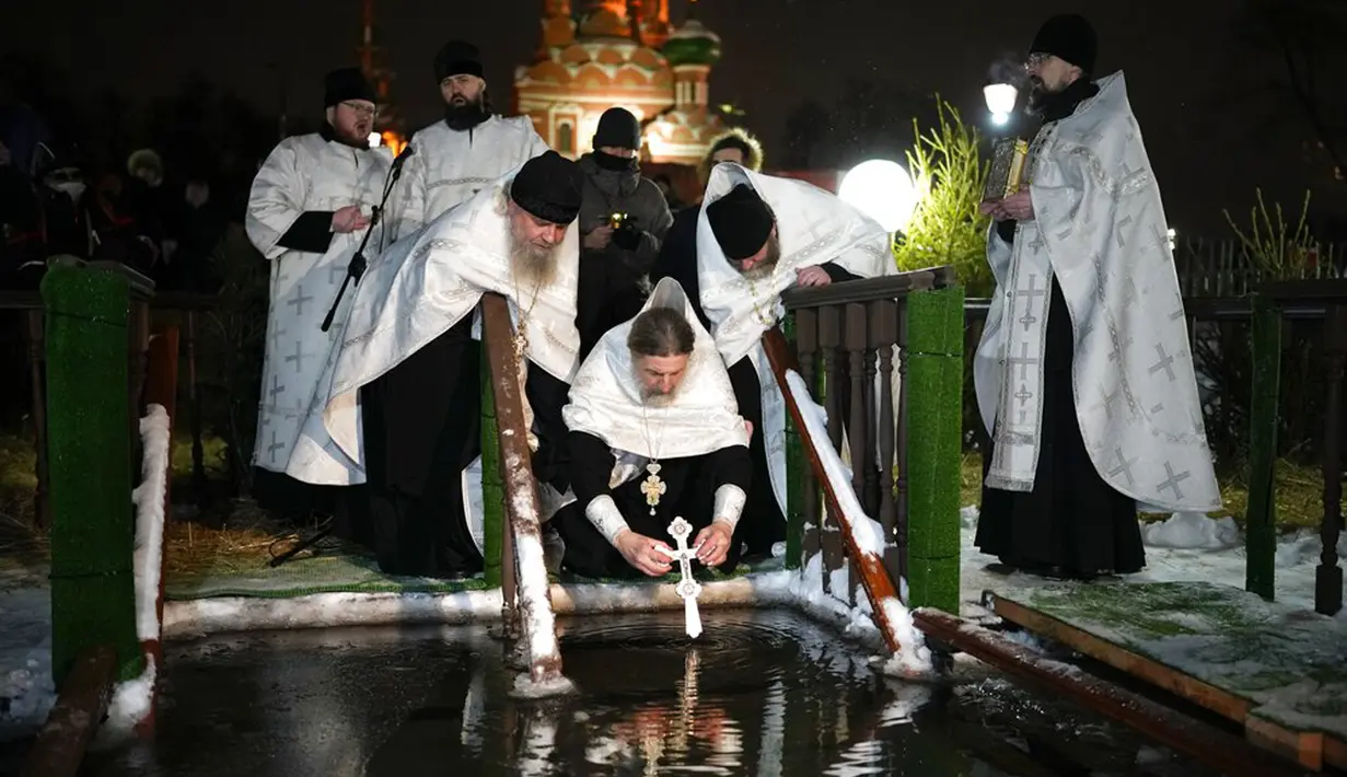 Seorang pendeta Kristen Ortodoks Rusia memberkati air es pada perayaan Epiphany di Gereja Tritunggal Mahakudus, Ostankino, Moskow, Rusia, 18 Januari 2022. Ribuan penganut Kristen Ortodoks Rusia merayakan Epiphany dengan membenamkan diri dalam air dingin. (AP Photo/Alexander Zemlianichenko)