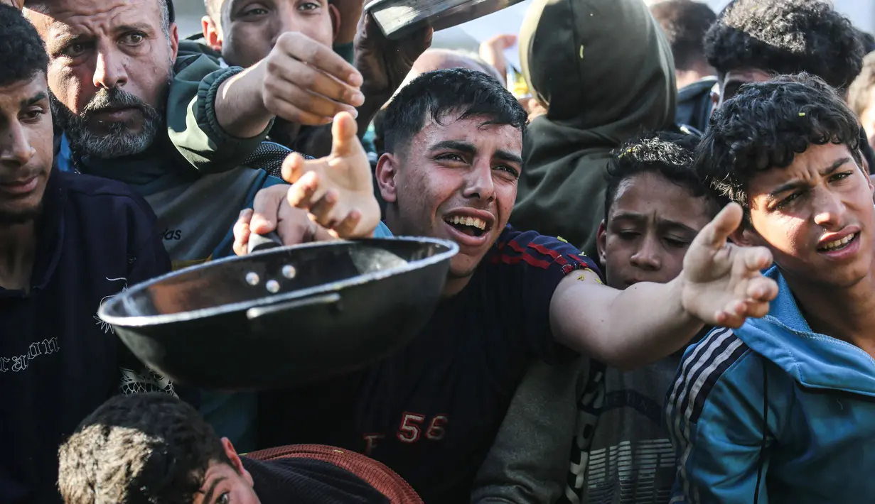 Warga Palestina yang mengungsi berebut untuk makanan di Khan Younis, selatan Jalur Gaza pada Jumat 6 Maret 2026. Krisis pangan di Gaza kembali mencapai titik kritis. Situasi ini imbas eskalasi konflik regional yang memicu penutupan seluruh pintu perlintasan perbatasan ke Gaza oleh Israel. (Bashar Taleb/AFP)