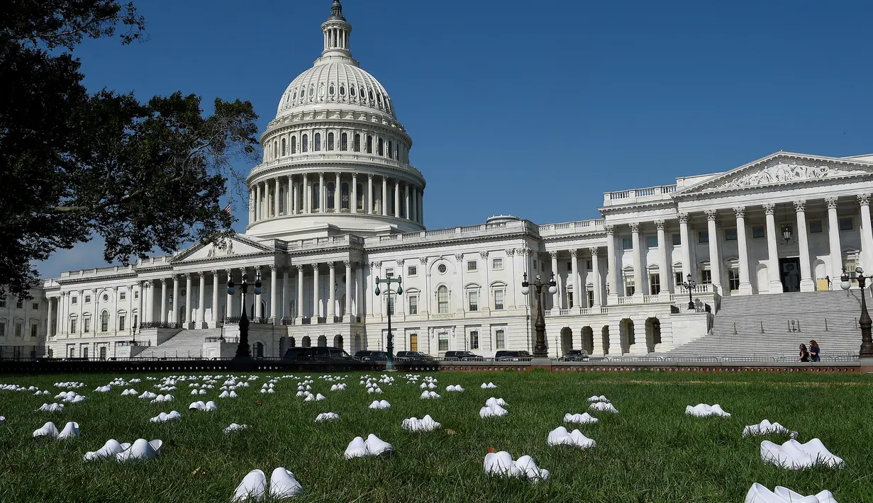 Serikat perawat Amerika Serikat (AS) meletakkan 164 pasang sepatu putih di luar US Capitol di Washington, DC pada Selasa (21/7/2020). Sepatu-sepatu itu melambangkan para perawat yang tewas akibat covid-19 dan menuntut Senat bertindak cepat melindungi perawat di garis depan. (Olivier DOULIERY/AFP)