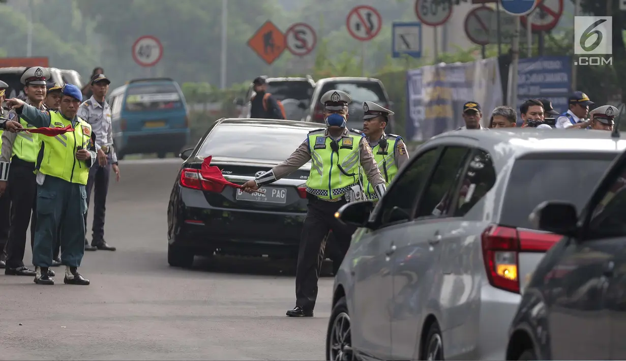 Petugas polisi lalu lintas memberhentikan kendaraan saat pemberlakuan sistem ganjil genap di pintu masuk Gardu Tol Cibubur 2, Jakarta, Senin (16/4). Aturan ganjil genap ini diujicobakan di Gerbang Tol pada Senin 16 April 2018.(Liputan6.com/Faizal Fanani)