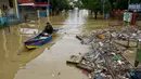 Seorang warga menggunakan perahu untuk melewati jalan yang tergenang banjir setelah hujan lebat dan tanggul jebol, di Lhoksukon, Aceh Utara, 7 Oktober 2022. (AFP/Azwar Ipank)