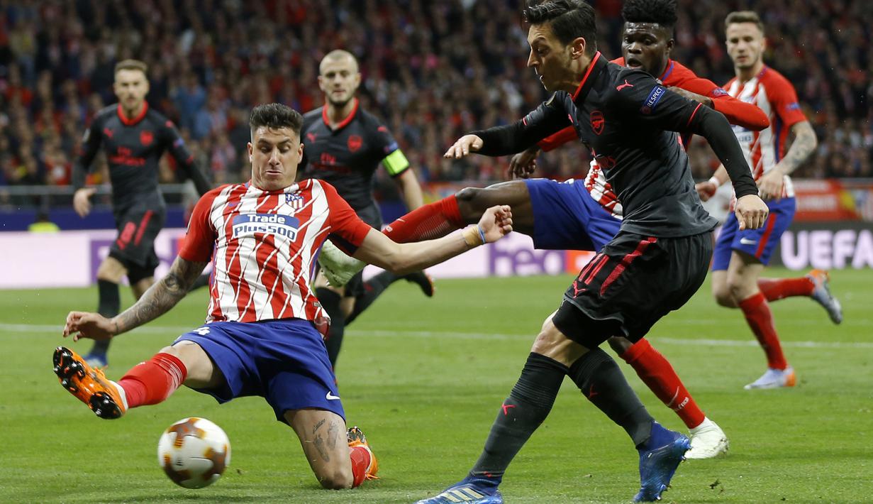Aksi pemain Arsenal, Mesut Ozil (kanan) melepaskan tembakan saat di adang pemain Atletico, Jose Maria Gimenez pada semifinal Liga Europa di Wanda Metropolitano stadium, Madrid, (3/5/2018). Atletico menang 1-0. (AP/Francisco Seco)