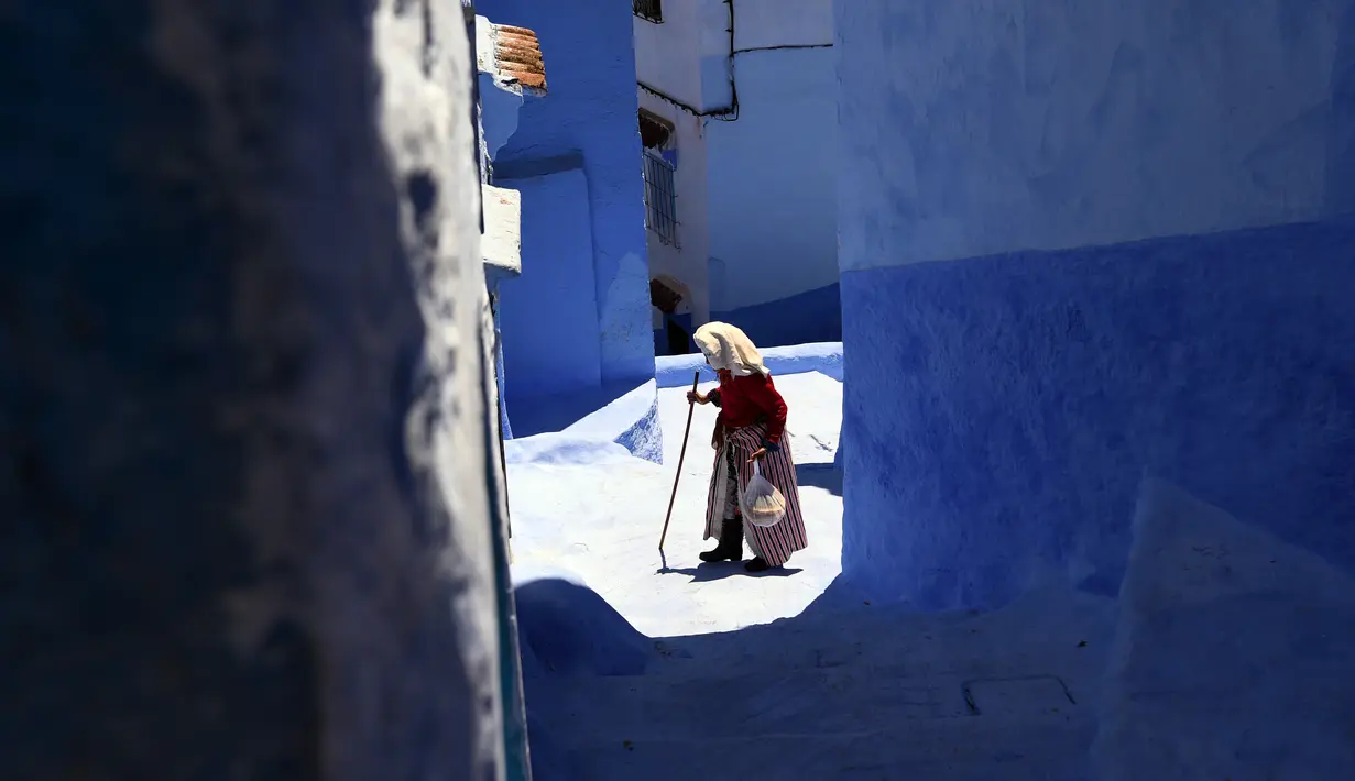 Wanita berjalan di sepanjang gang kecil, Kota Chefchaouen, Maroko, Minggu (1/5). Kota Chefchaouen Terkenal sebagai salah satu kota paling biru di Bumi karena kota ini dihiasi dengan cat bangunan yang berwarna biru. (FADEL SENNA / AFP)