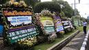 Warga mengambil gambar karangan bunga ucapan duka cita untuk Probosutedjo yang memenuhi Jalan Diponegoro, Jakarta, Senin (26/3). Salah satu karangan bunga bertuliskan dari Menko Polhukam RI Wiranto. (Liputan6.com/Arya Manggala)