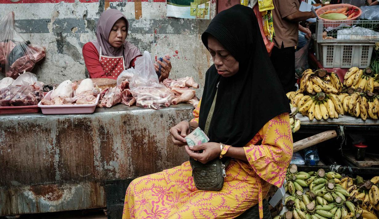 Seorang wanita menghitung uang kertas untuk membayar pembelian daging ayam di sebuah warung pinggir jalan di Jakarta pada Sabtu 8 November 2025. Pemerintah berupaya menjaga momentum agar rata-rata pertumbuhan ekonomi tahun ini bisa mencapai 5,2 persen. (YASUYOSHI CHIBA/AFP)